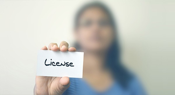 Picture of a person holding a card that says License.