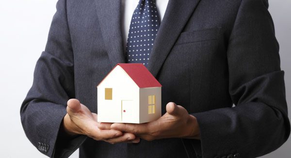 Picture of a man holding a house in his hands.