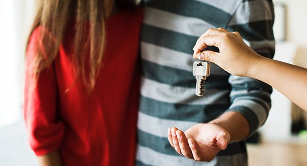 Picture of house keys being handed to a couple.