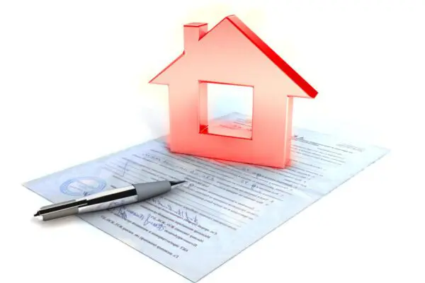 A pen and a red house-shaped figure rest on top of a signed real estate or property document.