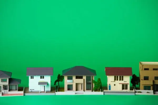 A row of small, model houses is displayed against a plain green background.