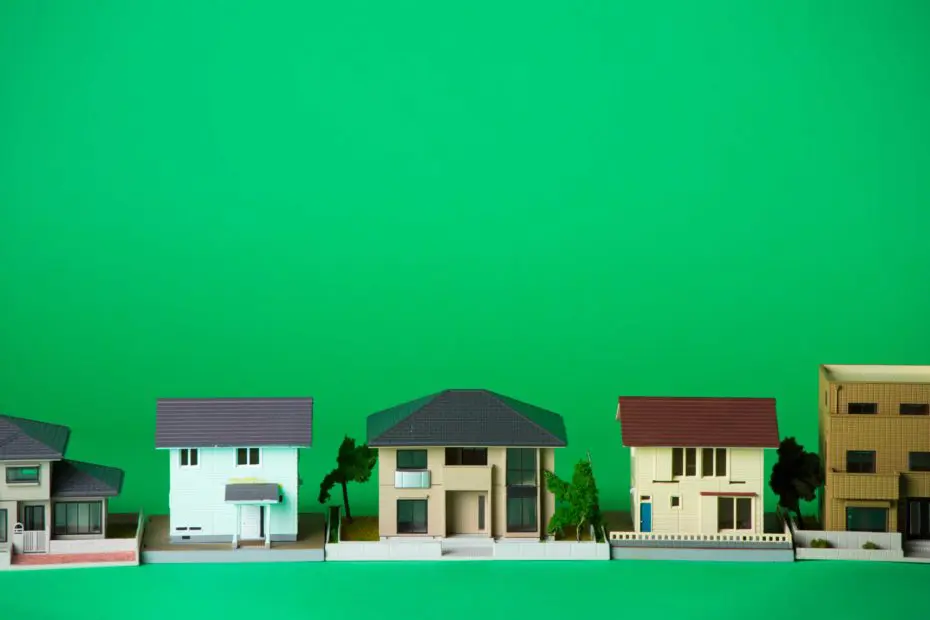 A row of small, model houses is displayed against a plain green background.