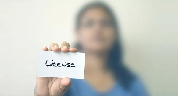 a person holding a card that says License.