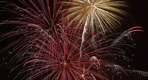 Red and gold fireworks burst and sparkle against a dark night sky.