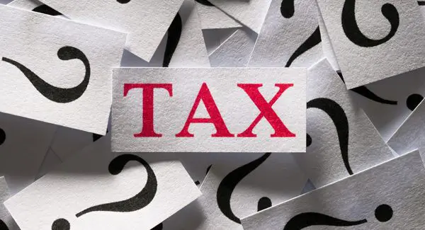 A card with the word "TAX" in red sits among many cards featuring black question marks.