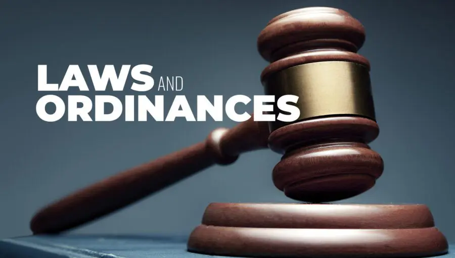 A wooden judge's gavel rests on its block next to the words "Laws and Ordinances" in bold white letters.
