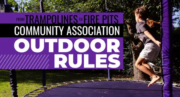 A girl jumps on a trampoline outside near trees, alongside a sign about community association outdoor rules for trampolines and fire pits.