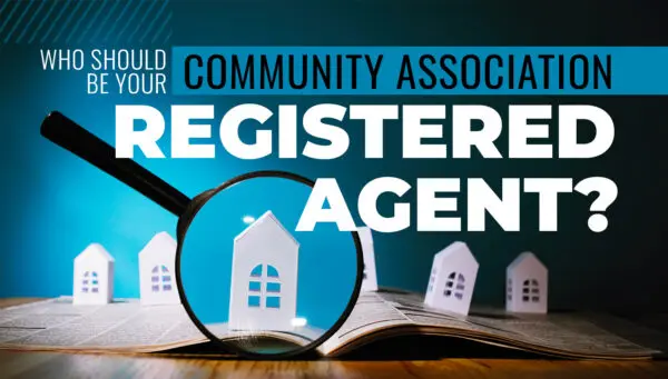 Magnifying glass over paper with small house models, text reads: Who should be your community association registered agent?.