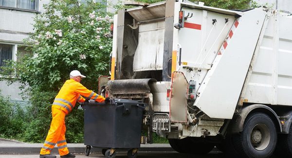 a garbage man putting trash into his truck.